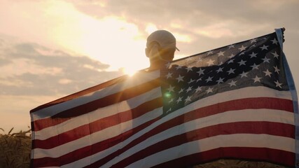 Middle-aged woman with USA flag stands in a wheat field at sunset. - Powered by Adobe