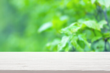 White wood table top on blur green bush background