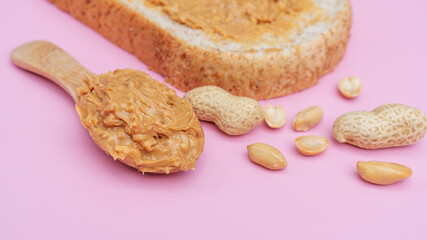 Peanut butter and whole wheat bread on a pink background.