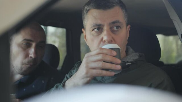 Pausing for a coffee break with donuts, operatives or spies take covert photos from the car window.