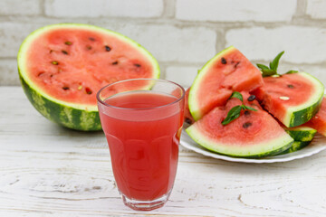 Glass of fresh watermelon juice on a white wooden table
