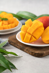 Diced fresh mango fruit on a white plate with leaves.