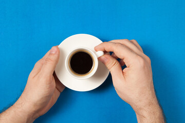 Top view of man hand holding a cup of coffee over flatlay.