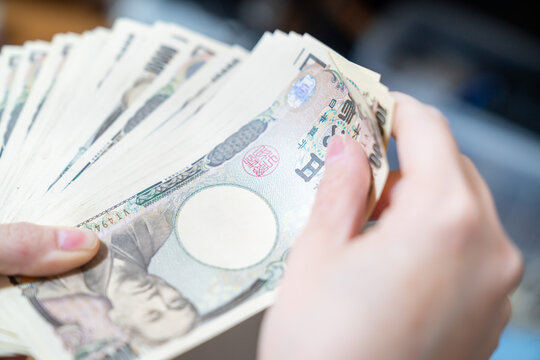 大量の1万円札を手に持っている写真。お金持ちのイメージ。
