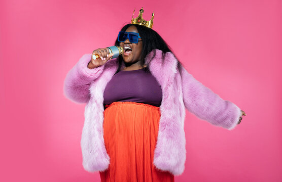 Image of a beautiful woman posing in a furry coat on a pink background