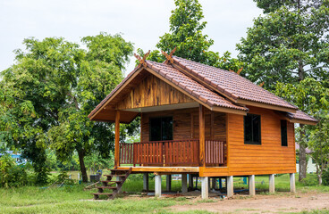 Small wooden house in Thai style, close to many trees.