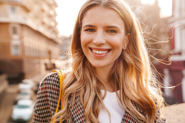 Close up of a smiling blonde young woman walking
