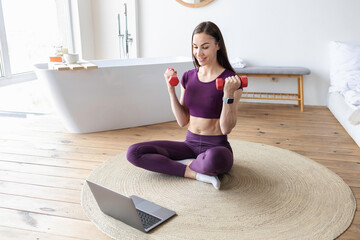 Online training at home and healthy lifestyle concept. Sporty woman watching online tutorial on laptop, exercising in living room