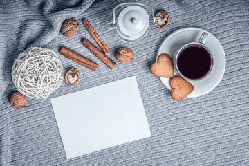 A beautiful plaid, a cup with coffee and cookies on a table with candles and a white envelope.