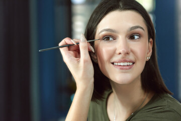 Closeup portrait of a young woman making an online tutorial and showing her favorite organic beauty product. A happy female smiling and doing makeup herself.