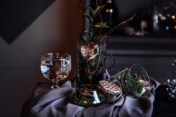 modern beautiful dark interior, room gray color, wardrobe shelves unusual gloomy decor table fabric cloth, dried flowers, vases with water, moss, branches, unusual style, halloween