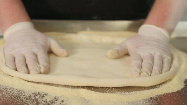 Chef forming dough for pizza and kneading it with hands