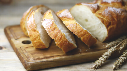 Fresh wheat bread sliced on a wooden board.