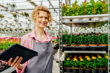 Agricultural blond woman engineer working with tablet, adminis plants industrial greenhouse with...