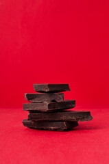 Stack of dark sweet chocolate on the bright red background.Empty space