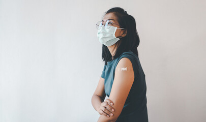 Asian woman showing her arm after getting covid-19 vaccine.
