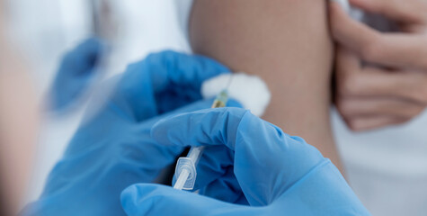 The doctor's hand holding a syringe and was about to vaccinate a patient in the clinic to prevent the spread of the virus