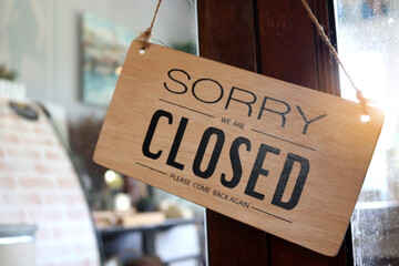 Wooden sign board that says ‘closed’ on cafe or restaurant hang on door at entrance.