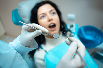 beautiful brunette curly female dentist treat patient in modern clinic