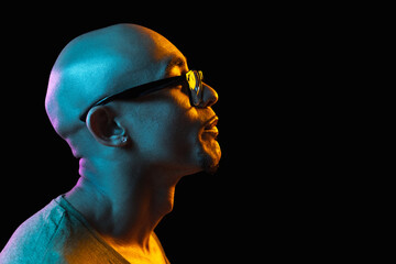 African-american young man's portrait on dark studio background in neon. Concept of human emotions, facial expression, youth, sales, ad.