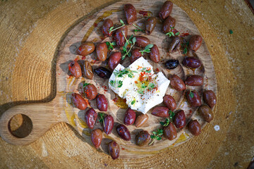Olives and cheese serving on wooden board