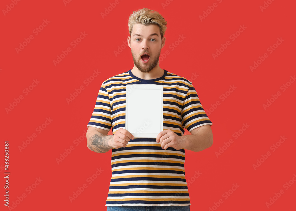 Poster surprised young man with tablet computer on color background