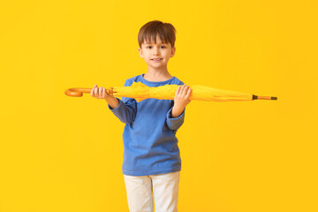 Cute little boy with umbrella on color background