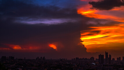 Blurred background of city views,high angles colorful sky,green leaves from the balcony,twilight lighting of car lights from tall buildings showing the distribution of accommodation in the capital.