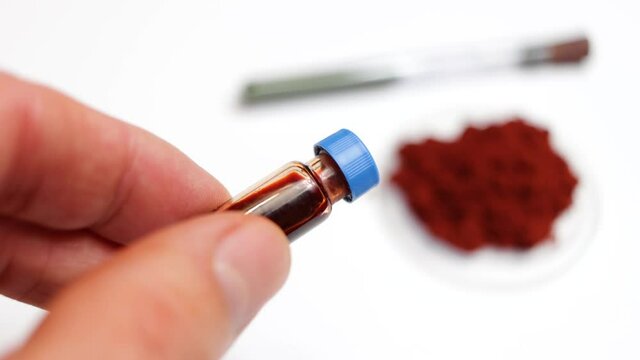 On a white background is shown the reagent for developing fingerprints called sangre de drago in powder form and in liquid form dissolved in a vial, in medicine it has healing properties
