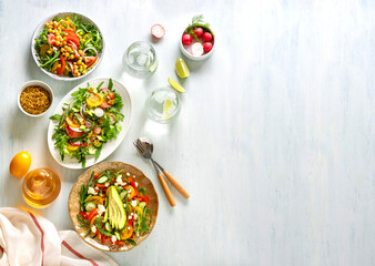 Fototapeta na wymiar Various summer healthy vegetables salads with avocado, cucumber, radish, bell pepper and tomato. Healthy food.