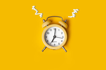 Top view of the yellow alarm clock on the yellow background with a free space for text. Getting up early in the morning. Wake up with a great mood