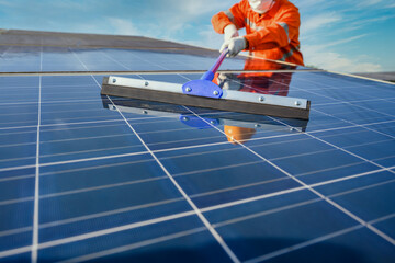 Asian male worker or engineer In a solar power station The solar panel is being cleaned using a mop...