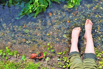 綺麗な小川の水で遊んでいる子供の足