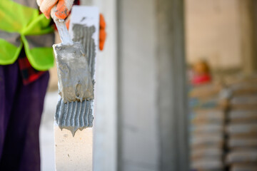 Construction worker We are plastering the adhesive mortar that uses lightweight concrete for construction. Techniques for applying adhesive mortar to a construction site.