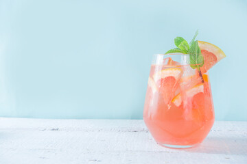 One glass with summer cold drink lemonade with grapefruit pieces, ice and mint copy space