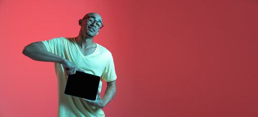 African-american young man's portrait on red studio background in neon. Concept of human emotions,...