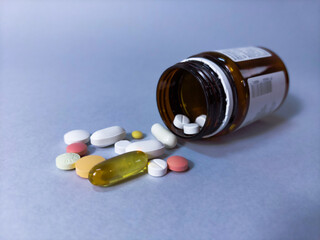 Still life with a bunch of different pills and a glass bottle