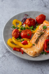 Baked red fish fillet Arctic char on a plate with vegetables close up, delicious hearty healthy dinner