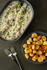 Stewed hake in a creamy sauce with baked potatoes, delicious hearty lunch, top view