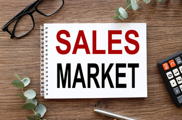 SALES MARKET. text on white notepad paper on wood table.