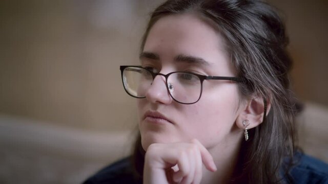 pensive girl in glasses is thinking about plans close-up, cunning plans for the future, carefully thinking about a plan sitting alone