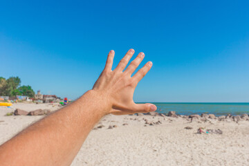 The young man stretched his hand forward to the sea and sky on the beach. The concept of freedom and rest at sea