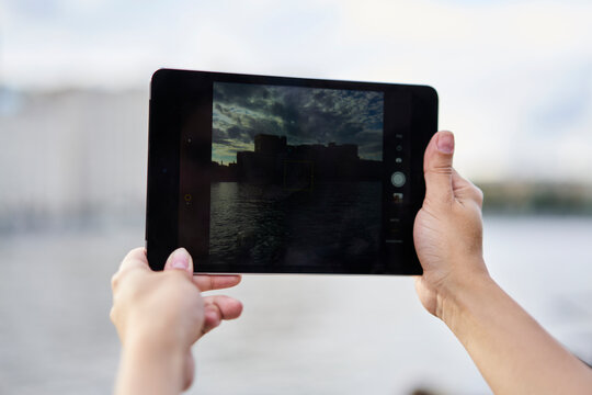 Cropped female tourist using modern touch pad and main camera for clicking image photos during travel vacations and sightseeing, woman photographing landscape via application on digital tablet