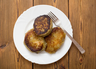 A plate with a Belarusian dish potato pancakes with meat filling. Wooden background, close-up