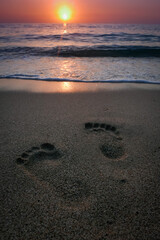 Fototapeta na wymiar orme di piedi in spiaggia al tramonto