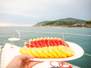 Watermelon and pineapple cut into pieces with views of the sea.