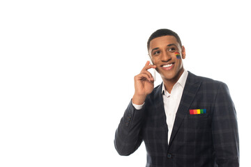 cheerful african american businessman with lgbt flag painted on face talking on mobile phone...