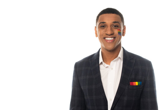 happy african american businessman with lgbt flag painted on face smiling at camera isolated on white