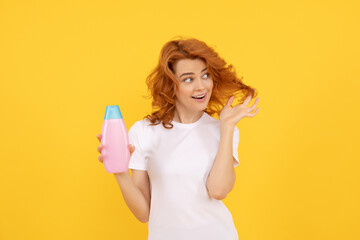 Beautiful woman with organic shampoo over light yellow background. curly hair
