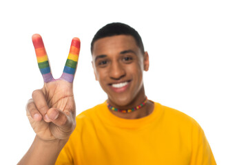 joyful african american man showing peace sign with fingers painted in lgbt colors isolated on...